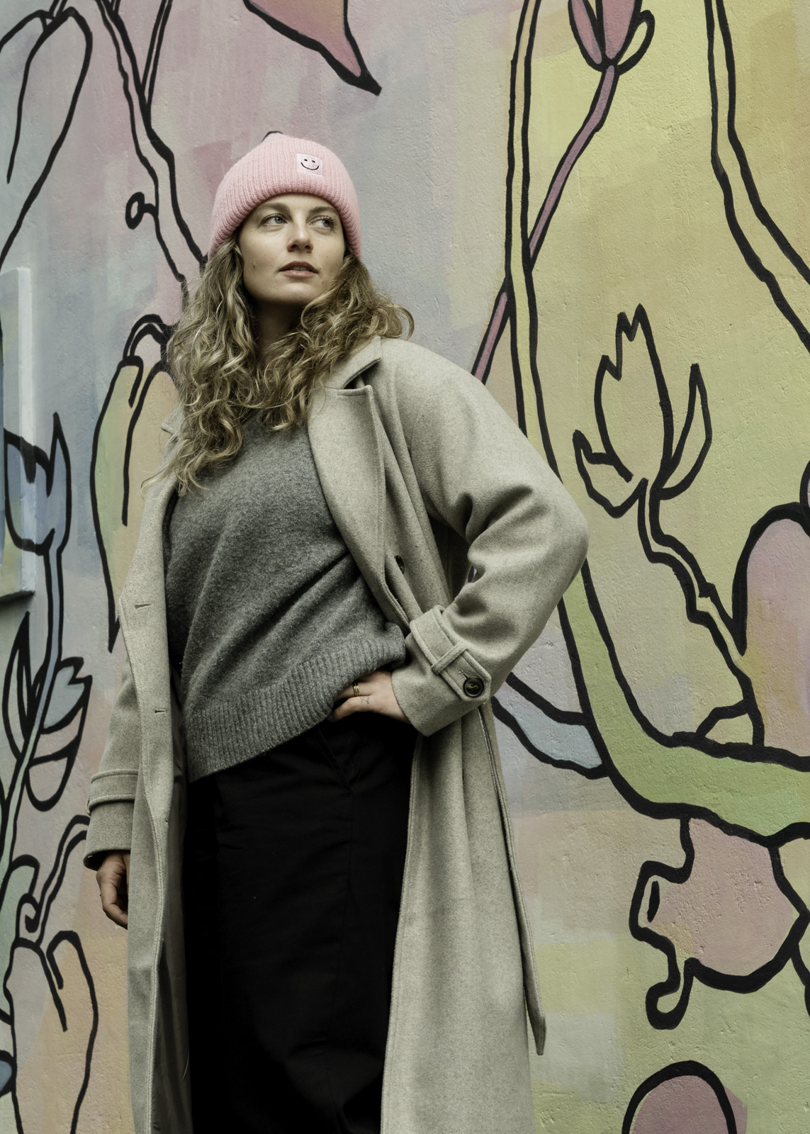 Frau im mantel vor bemalter wand
