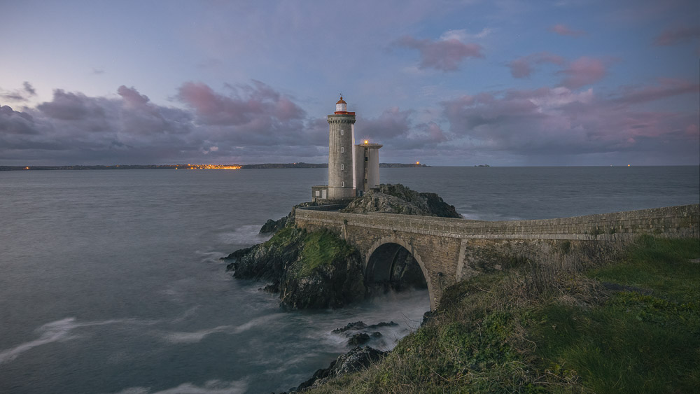 Leuchtturm auf einer Felsspitze zur blauen Stunde, Langzeitbelichtung